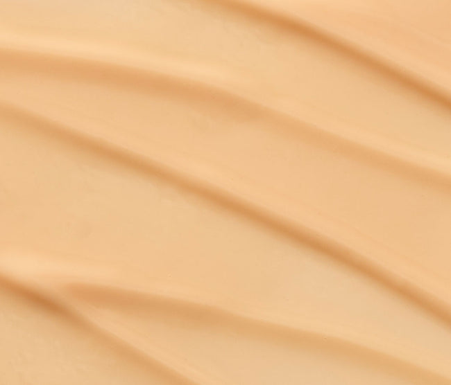 Close-up texture of Tropic Skincare Eye Lift Exosome Midnight Balm, showing its smooth, creamy consistency in a warm beige tone.