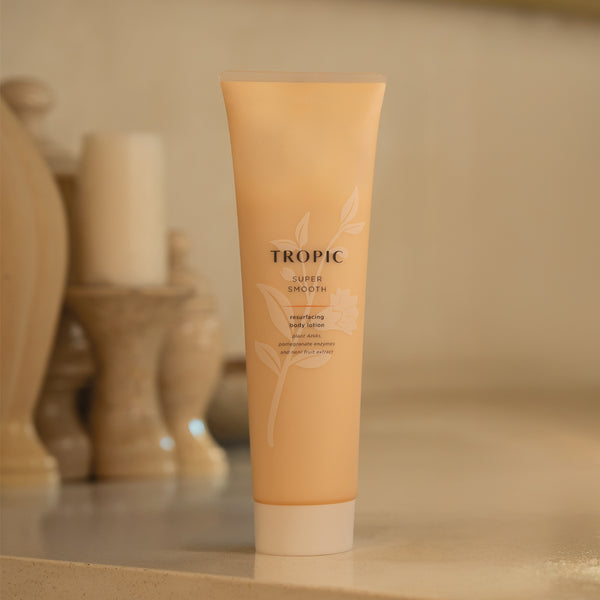 Super Smooth resurfacing body lotion is placed upon a counter. The bottle is light peach with a floral design on the tube and screw lid.
The product contains plant AHAs, pomegranate enzymes and noni fruit extract.