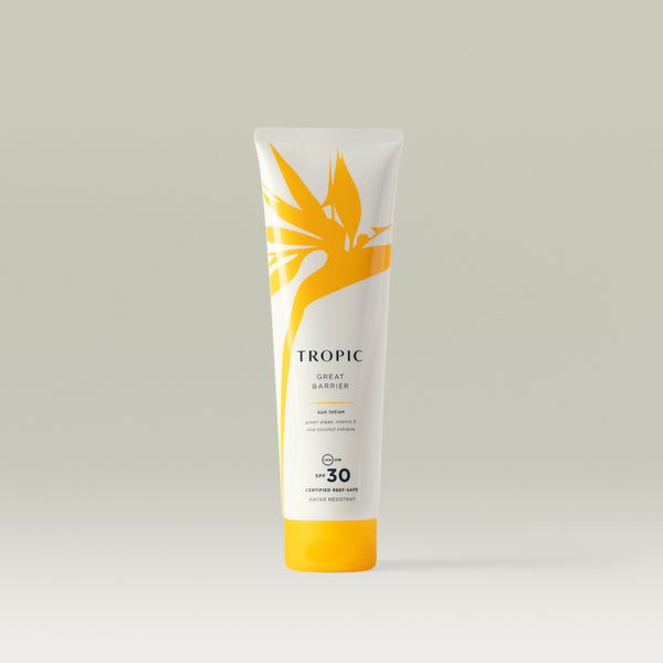 A white tube of Tropic Great Barrier Sun Lotion with SPF 30, featuring a yellow tropical leaf design and text stating 'certified reef-safe' and 'water resistant'.