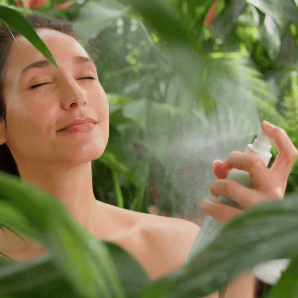 Video of a woman in the rainforest surrounded by leaves spraying Morning Mist to her face.