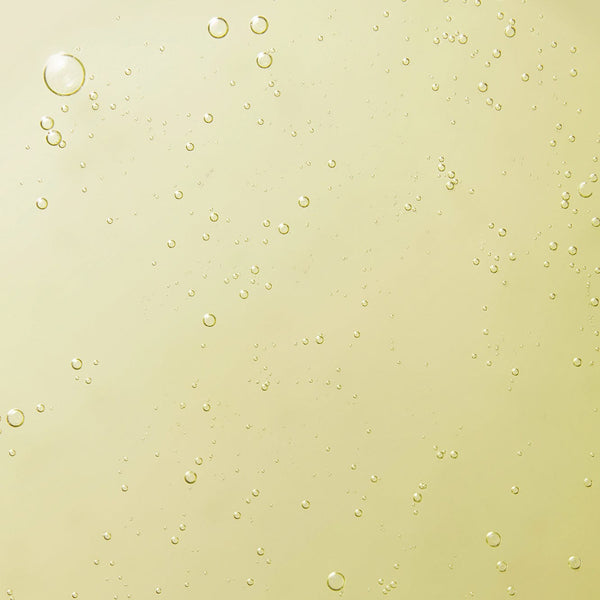 Close-up texture of Tropic's signature hand wash with golden liquid and small bubbles suspended throughout.