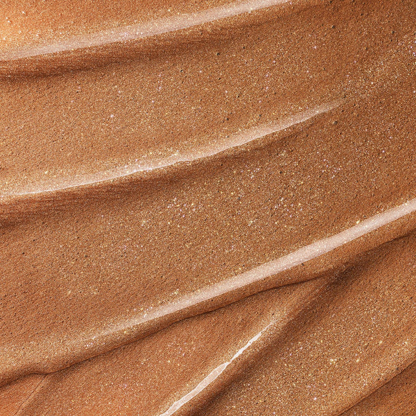 Close-up texture of Instant Glow perfecting leg serum. The texture is smooth and luminous with fine glitter particles, giving it a radiant and glowing finish.