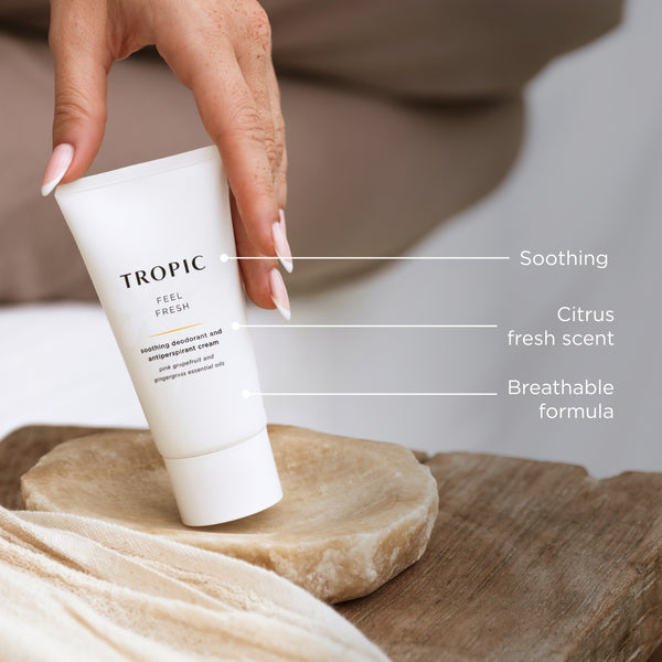 Hand placing Tropic “Feel Fresh” deodorant on a stone tray with text highlighting soothing, citrus scent, and breathable formula.