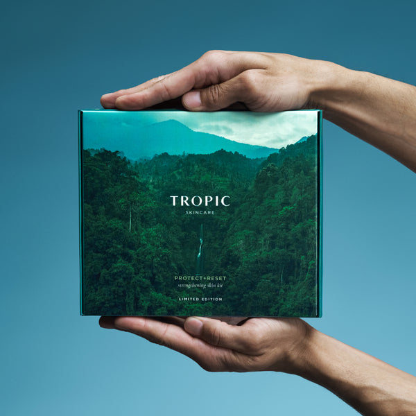 Hands holding Tropic Protect & Reset strengthening skin kit gift box.