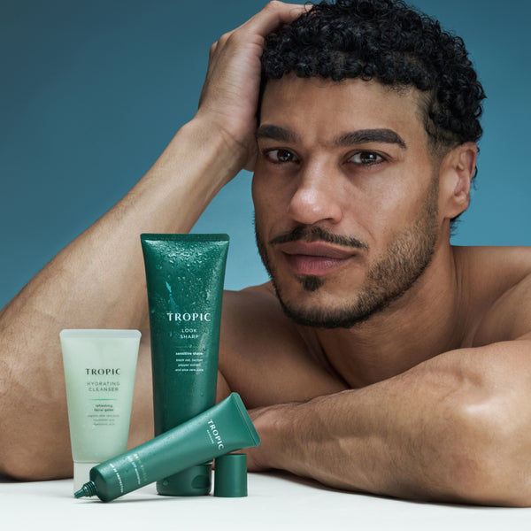 Model posing with Tropic Protect & Reset skincare products including cleanser, shave gel and SPF moisturiser.