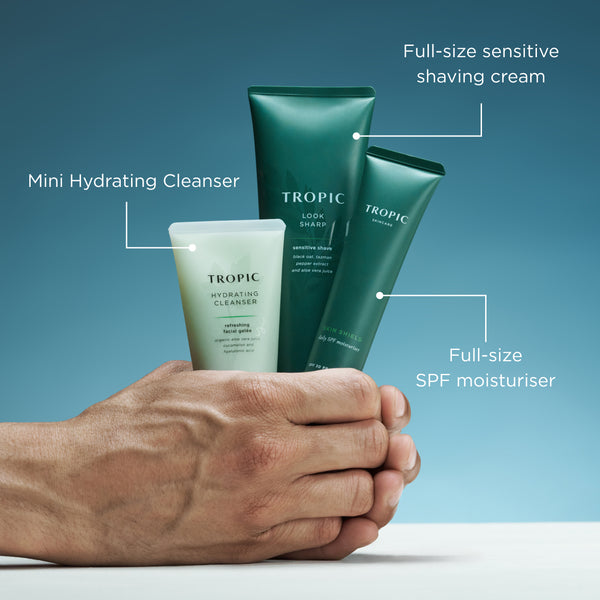 Hand holding Tropic Protect & Reset skincare products with cleanser, shave cream and SPF moisturiser callouts.