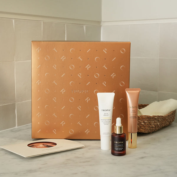 The Healthy Glow Ritual - natural bronzing trio by Tropic. A bronze-toned gift set box with three skincare products displayed in front: Skin Feast nourishing moisturiser, Sun Drops gradual tanning serum, and Sun Glaze illuminating bronzing drops.