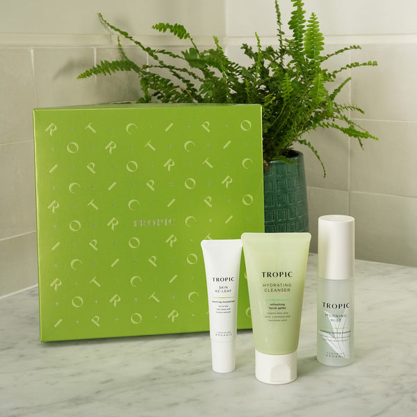 The Hydration Facial – Dewy Skin Collection by Tropic Skincare, featuring Skin Re-Leaf, Hydrating Cleanser, and Morning Mist products with a festive green gift box on a bathroom counter.