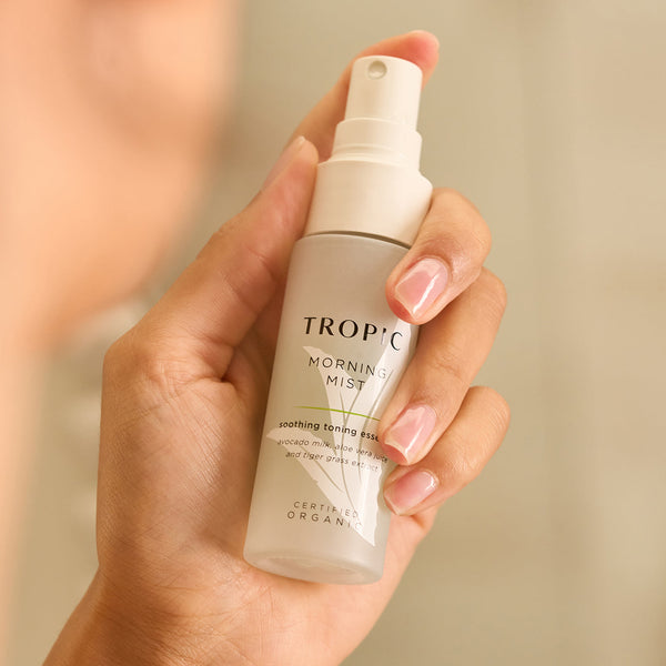 Close-up of a hand holding Tropic Morning Mist, a soothing toning essence with avocado milk, aloe vera juice, and tiger grass extract.
