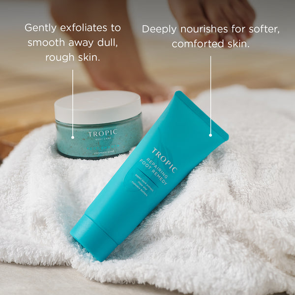 Tropic Foot Smooth enzymatic scrub and Repairing Foot Remedy displayed on a soft towel with text explaining benefits: ‘Gently exfoliates to smooth away dull, rough skin’ and ‘Deeply nourishes for softer, comforted skin.