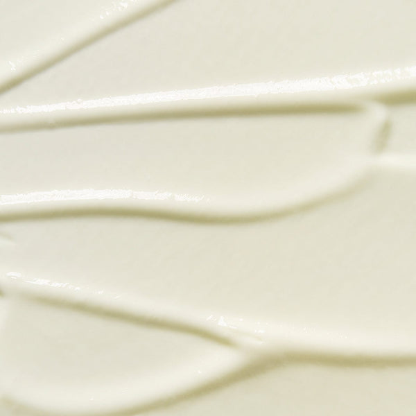 Close-up texture of Tropic Sun Day dewy facial SPF 50 sunscreen, showing smooth creamy consistency with subtle swirls.