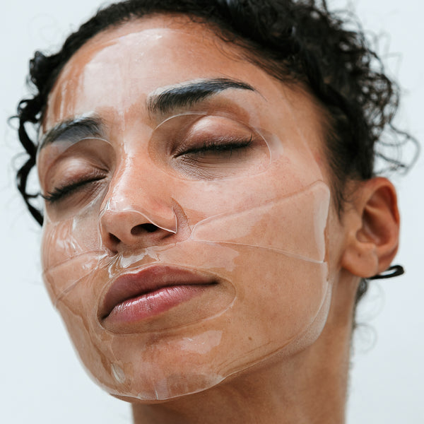 Model wear Hydrogel face mask on her skin. You can see the mask comes in two parts and is layered onto her skin. She has her eye closed as the mask adds hydration to her skin.