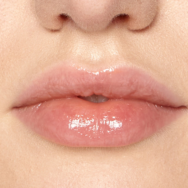 Close-up of model’s lips wearing Tropic Lip Fudge in shade Clear, giving a glossy, hydrated finish.