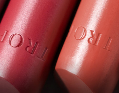 Close up of two tropic lip products the Tropic engraved on the product.