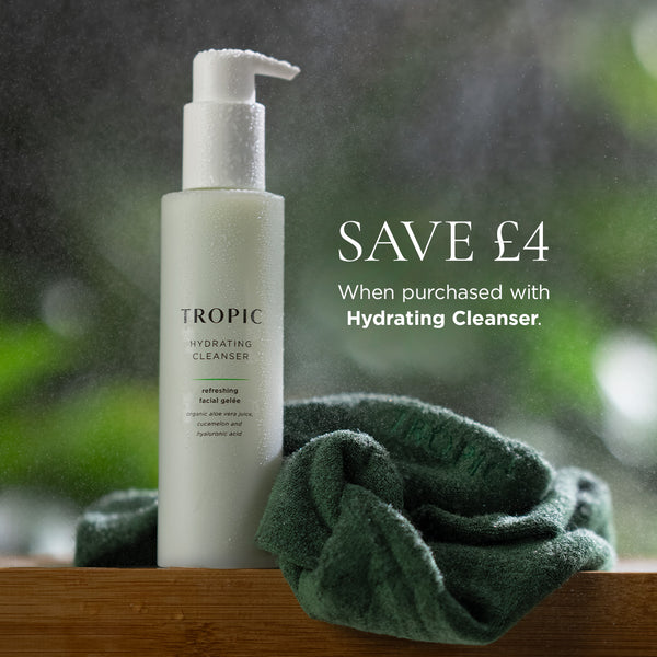 Bottle of Tropic Hydrating Cleanser next to a green bamboo headband, with promotional text reading 'SAVE £4 when purchased with Hydrating Cleanser' against a blurred, dewy background.