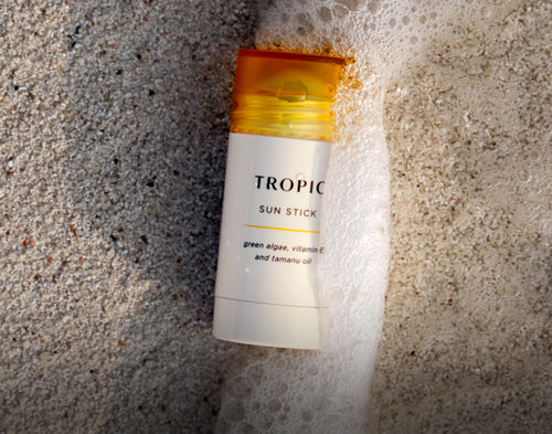 Tropical Sun Stick on a textured sand surface.