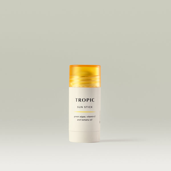 Tropic Sun Stick with green algae, vitamin E, and tamanu oil in a sleek white tube with a yellow cap, displayed on a neutral background.