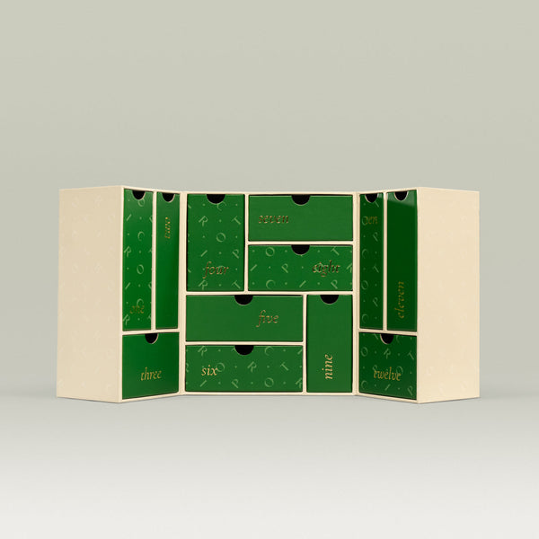 Tropic 12 Days of Tropic Advent Calendar – opened to reveal twelve green numbered drawers inside a cream box, each drawer designed to hold a daily skincare treat.