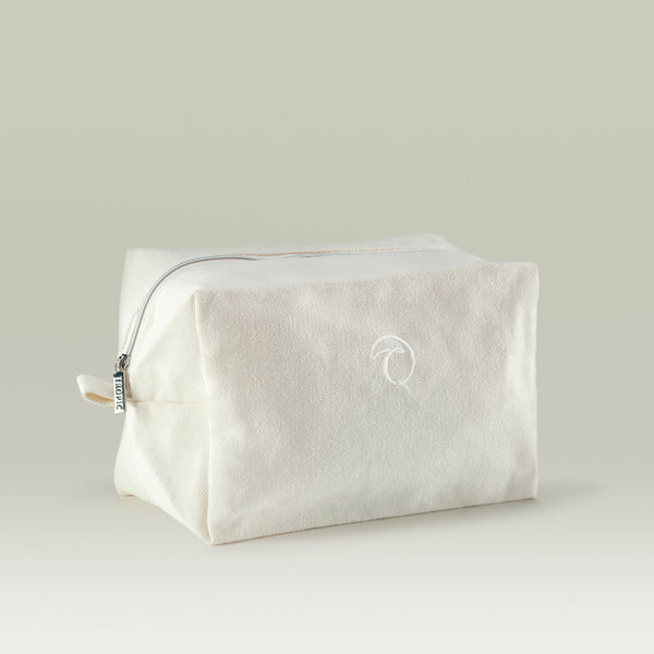 A white-coloured Tropic zippered travel bag with subtle embroidered logo, designed for storing skincare and beauty essentials.