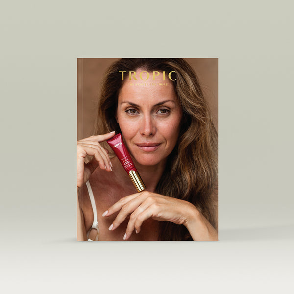 Cover of the Tropic Beauty Brochure featuring a woman with long brown hair holding red Tropic Eye Lift  product against her face, with the gold title text “TROPIC The Beauty Brochure” at the top.