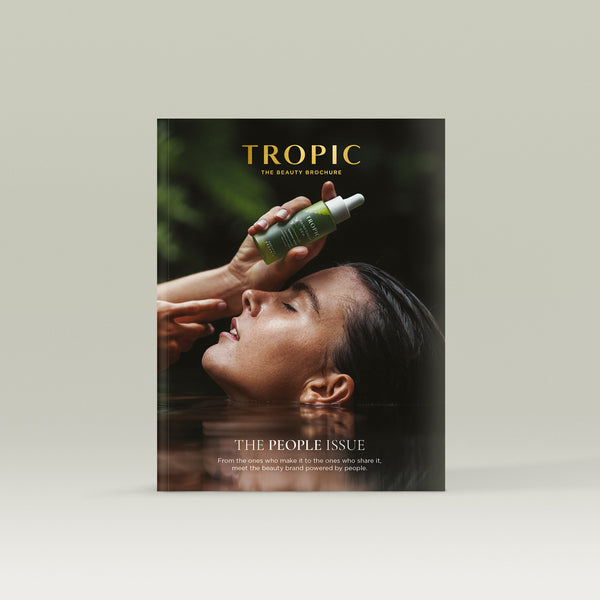 Tropic Beauty Brochure cover showing a woman relaxing in water holding Rainforest Dew serum above her head, evoking a calm, nature-inspired skincare ritual.