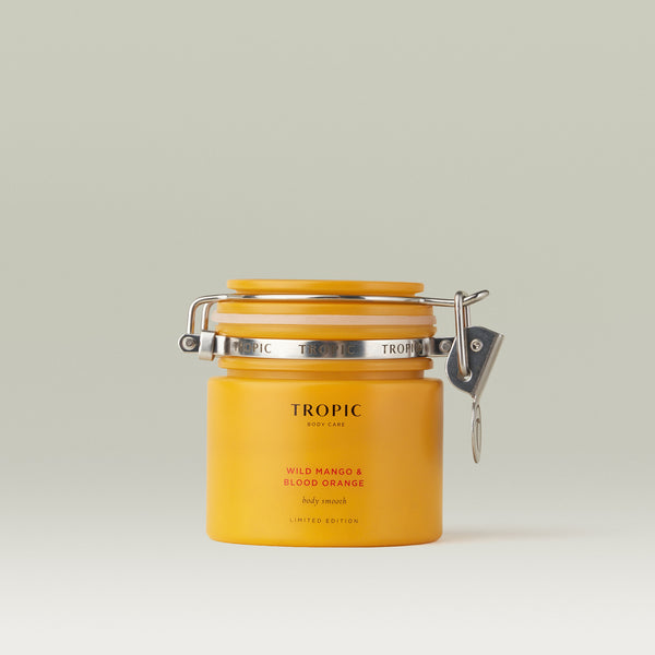 Tropic Wild Mango & Blood Orange Body Smooth in a yellow glass jar against a soft neutral background.