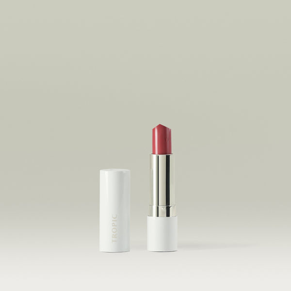 Butter Tint Lip & Cheek Balm in shade Loved by Tropic. The product is shown upright with the lid removed and placed beside it, revealing a rich rose-pink balm in a sleek white and silver tube against a neutral background.