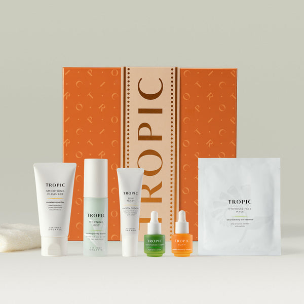 Tropic Skincare gift set titled The Favourites Facial – bestselling skincare collection, featuring a selection of customer-favourite products including Smoothing Cleanser, Morning Mist, Skin Feast, Rainforest Dew, Elixir, and Hydrogel Face Mask, a bamboo face cloth and displayed with an orange gift box.
