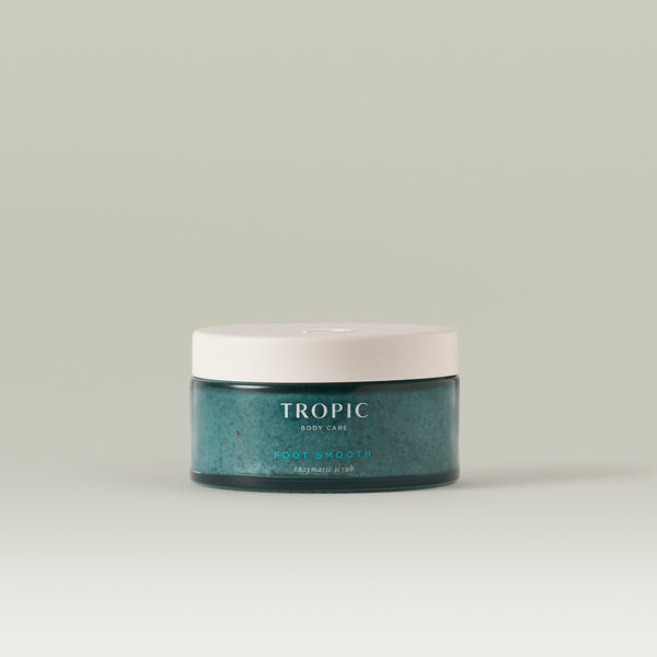 Tropic Foot Smooth enzymatic scrub in a glass jar with a white lid displayed against a neutral background
