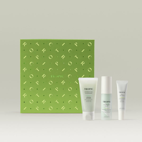 Tropic Skincare gift set titled The Hydration Facial – dewy skin collection, featuring the Hydrating Cleanser, Morning Mist, and Skin Re-Leaf, displayed in front of a vibrant green gift box with metallic detailing.
