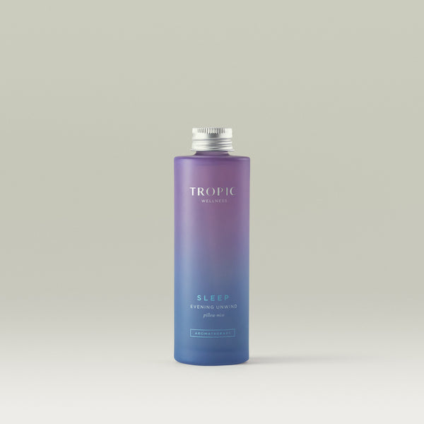Tropic Evening Unwind Pillow Mist bottle with gradient purple design on a light gray background