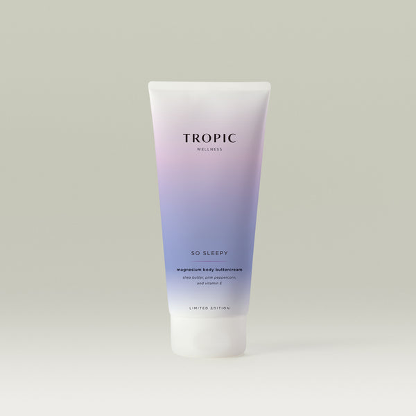A pastel gradient tube of Tropic Wellness “So Sleepy” magnesium body buttercream (limited edition), fading from soft pink to lavender, standing upright against a neutral background.