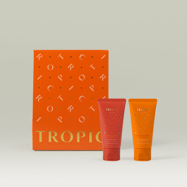 Tropic Skincare gift set titled Spiced Citrus & Clove – seasonal body ritual, featuring two limited edition creamy body washes in festive red and orange tubes, displayed in front of a bold orange gift box with gold detailing.
