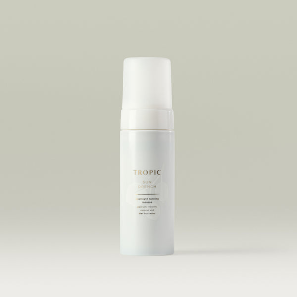Tropic Sun Drench overnight tanning mousse. White bottle with white lid and faint white leaf design behind gold text.