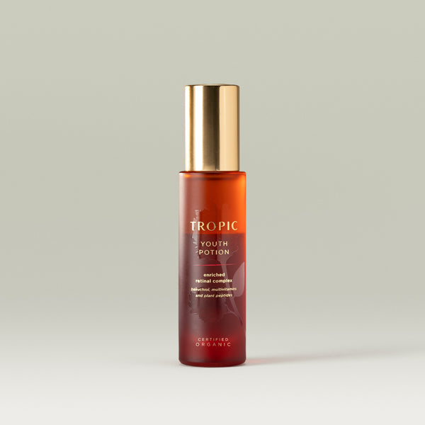 Tropic Youth Potion bottle with a gold cap, containing enriched retinal complex with bakuchiol, multivitamins, and plant peptides, displayed on a neutral background.
