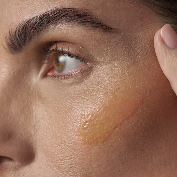 Close-up of skin with a smooth, glossy layer of product applied showing a rich, nourishing texture and radiant finish.